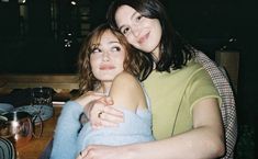 two women hugging each other in front of a table