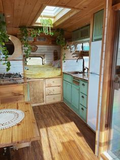 the interior of a small camper with wood floors and green cabinets, including a sink