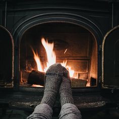 someone is sitting in front of the fireplace with their feet up on the fire place