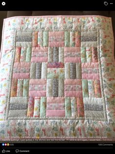 a pink and gray quilted blanket on top of a table