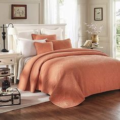 a bed with an orange comforter and pillows