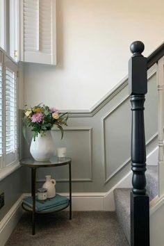 a vase filled with flowers sitting on top of a table next to a stair case