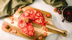 there is a strawberry cake on the cutting board with strawberries cut in half and ready to be eaten