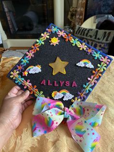 someone is holding up a graduation cap decorated with stars and rainbows on the front