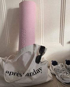 a gym bag and pair of sneakers next to a pink yoga mat