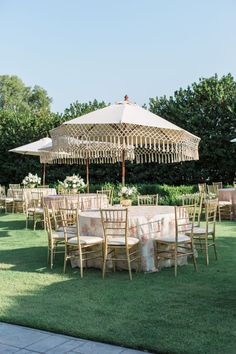 an outdoor dining set up in the grass with chairs and umbrellas on each side