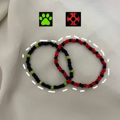 two beaded bracelets with ladybug and paw prints on white fabric background