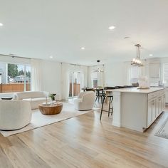 a living room filled with furniture next to a kitchen and dining room table on top of a hard wood floor