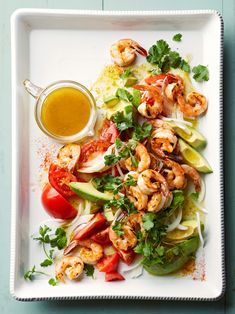 shrimp salad with avocado, tomatoes and cilantro dressing on a white plate