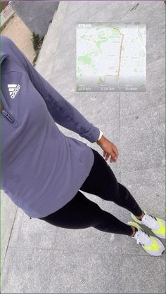 a woman is sitting on the sidewalk looking down at her cell phone while wearing leggings and running shoes