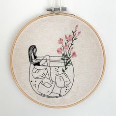 a embroidery project with a woman sitting in a fish bowl holding a vase filled with flowers