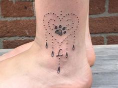 a dog's paw and heart tattoo on the side of a foot with rain drops