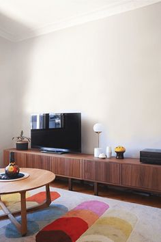 a living room with a television, coffee table and colorful rug in front of it