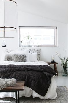 a bedroom with white walls, black and white bedding and rugs on the floor