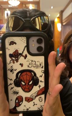 a person holding up a phone case with spiderman on it