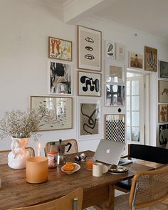 a laptop computer sitting on top of a wooden table next to a vase filled with flowers