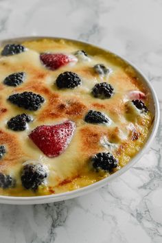 a white bowl filled with fruit on top of a marble counter