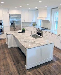 a large kitchen with white cabinets and marble counter tops, along with hardwood flooring