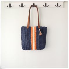 an orange and blue bag hanging on the wall next to two hooks with coat hangers