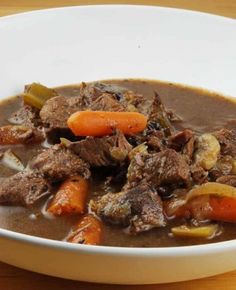 a white bowl filled with beef and carrots