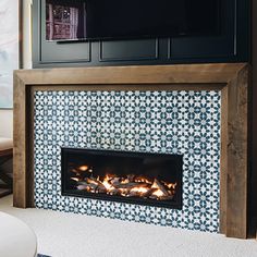 a living room with a fireplace and television on the wall above it is decorated in blue and white tiles