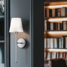 a lamp on the wall next to a book shelf