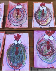 four square paintings with roosters painted on them in pink and green, sitting on a wooden surface