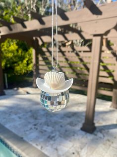 a glass ornament hanging from a chain next to a pool