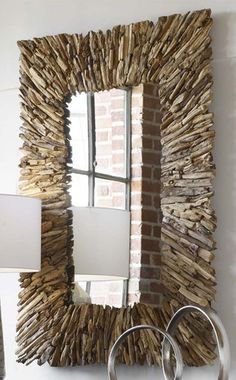 a mirror made out of driftwood is hanging on the wall next to a lamp