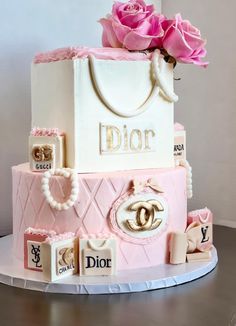 a three tiered pink and white cake decorated with chanel bags, roses and jewels