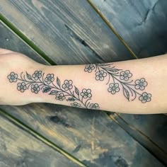 a woman's arm with flowers and leaves on the left side of her arm