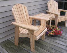 two wooden chairs sitting on top of a wooden deck next to a potted plant