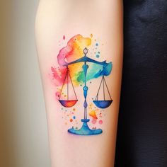 a watercolor tattoo on the arm of a woman with an scales of justice design