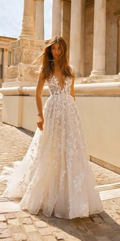 a woman in a wedding dress standing on the side of a building with columns behind her