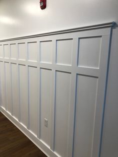 an empty room with white paneling on the wall and wood floors in front of it