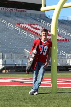 a young man standing next to a pole on top of a football field in front of an empty bleachers