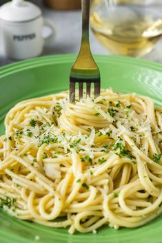 a fork is stuck into some pasta on a green plate