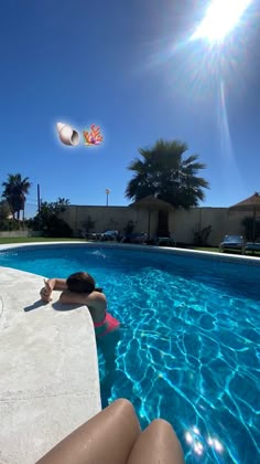 a woman laying on the edge of a swimming pool with balloons flying above her head