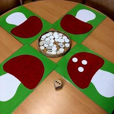 a wooden table topped with green and red paper cut out to look like mushroom's