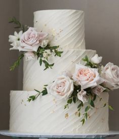 two tiered wedding cake with white frosting and pink flowers on each one side