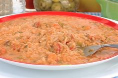 a red bowl filled with rice and vegetables on top of a blue table cloth next to bowls of olives