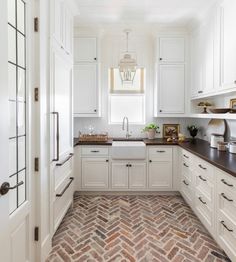 a kitchen with white cabinets and brick flooring