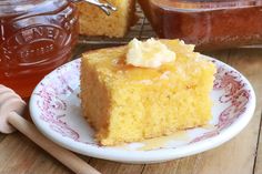 a piece of cake sitting on top of a plate next to a jar of honey