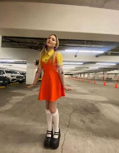 a woman wearing an orange dress and black shoes in a parking garage with her arms outstretched