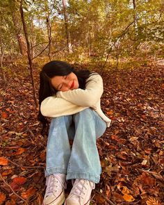 a woman sitting on the ground with her arms folded over her head and eyes closed