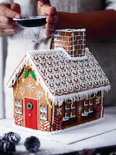 someone is decorating a gingerbread house with icing