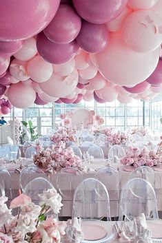 a room filled with lots of tables covered in pink and white balloons hanging from the ceiling