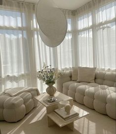 a living room filled with lots of furniture next to large window covered in sheer curtains