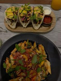 pasta with sauce and vegetables on a plate next to two plates of other food items