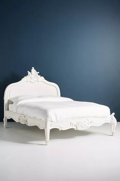 a white bed sitting on top of a white floor next to a blue wall in a room